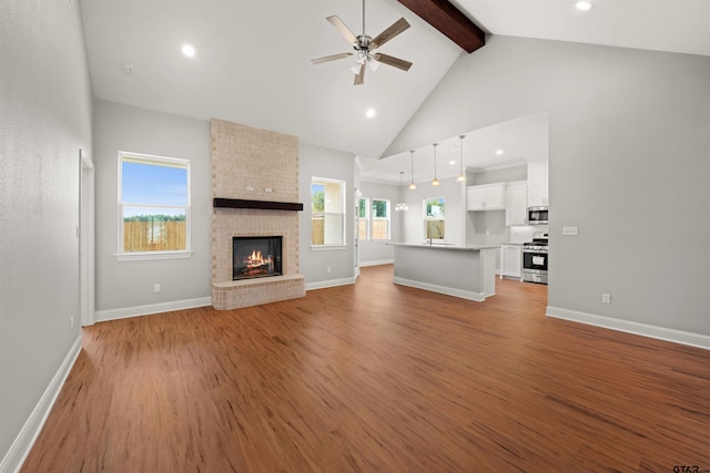 unfurnished living room featuring high vaulted ceiling, light hardwood / wood-style flooring, a fireplace, and beam ceiling