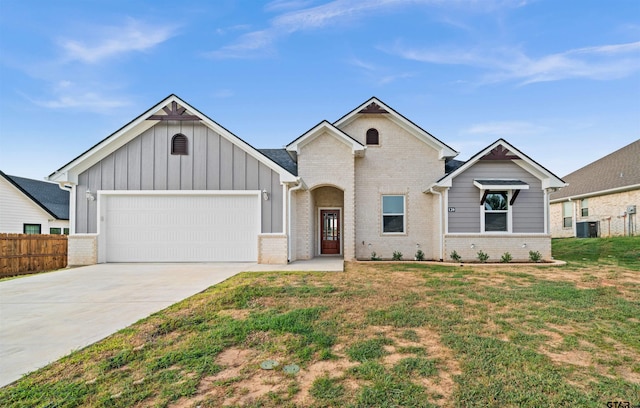 view of front of home featuring a front lawn, a garage, and cooling unit