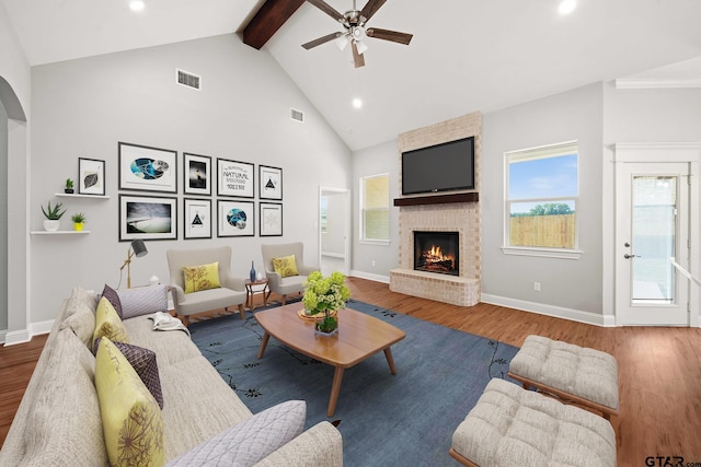 living room featuring hardwood / wood-style floors, plenty of natural light, a brick fireplace, and beam ceiling