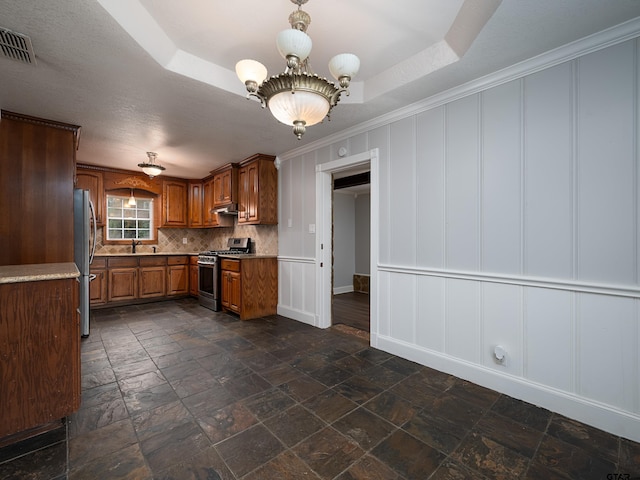 kitchen with crown molding, sink, decorative backsplash, appliances with stainless steel finishes, and a tray ceiling