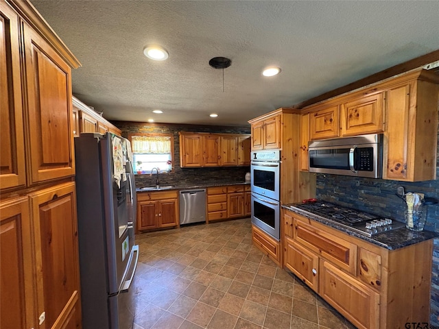 kitchen featuring brown cabinetry, decorative backsplash, stainless steel appliances, and a sink