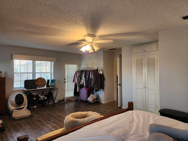 bedroom featuring a textured ceiling, two closets, ceiling fan, and dark wood-style flooring