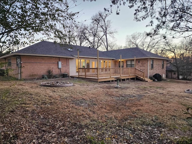 rear view of house featuring brick siding and a deck