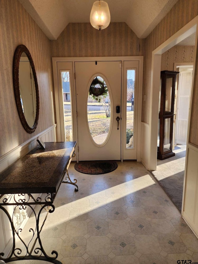 foyer entrance with wallpapered walls and vaulted ceiling