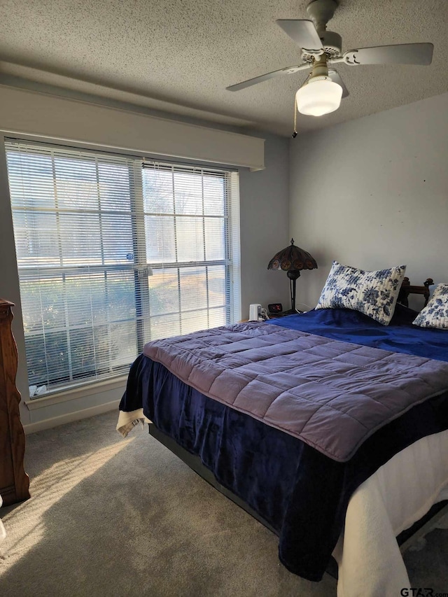 carpeted bedroom with ceiling fan and a textured ceiling