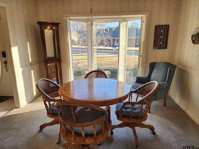 dining area featuring light carpet, a wainscoted wall, and wallpapered walls