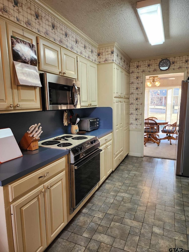 kitchen featuring crown molding, appliances with stainless steel finishes, cream cabinets, and a textured ceiling