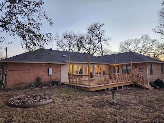 back house at dusk with a wooden deck and central air condition unit