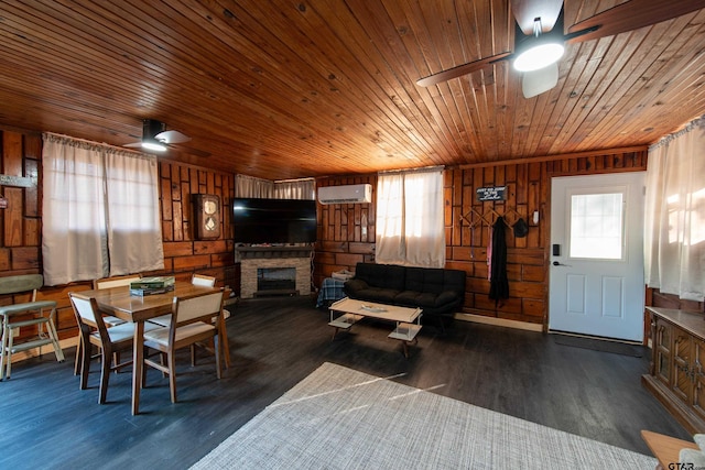 dining area with a wall unit AC, wooden walls, wooden ceiling, dark hardwood / wood-style floors, and a stone fireplace