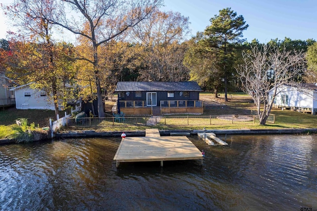 view of dock with a water view and a lawn