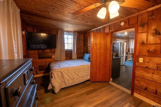 bedroom featuring wood walls, wooden ceiling, hardwood / wood-style flooring, ceiling fan, and stainless steel fridge