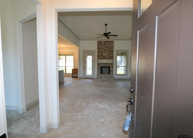 interior space with ceiling fan with notable chandelier and a brick fireplace