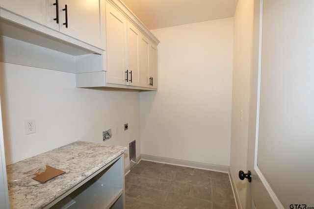 clothes washing area featuring electric dryer hookup and cabinets