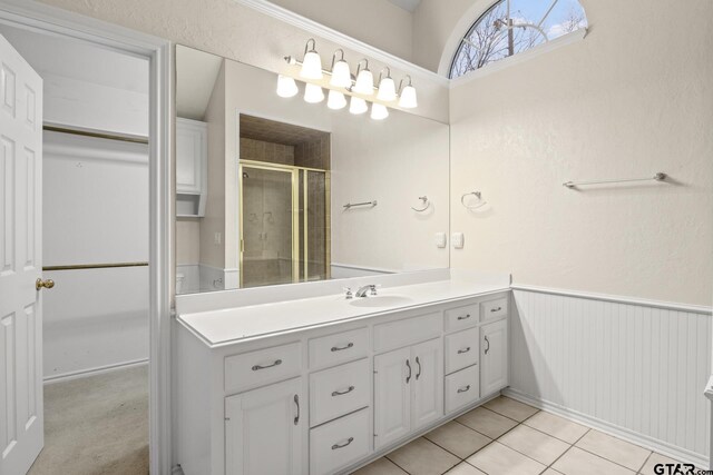 bathroom with walk in shower, vanity, and tile patterned flooring