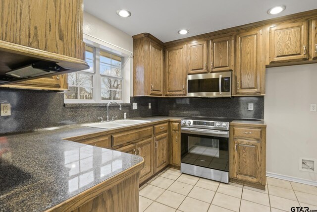 kitchen featuring stainless steel appliances, light tile patterned flooring, sink, and decorative backsplash