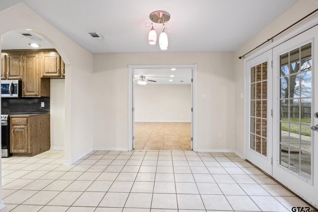 kitchen featuring light tile patterned flooring, ceiling fan, appliances with stainless steel finishes, and backsplash