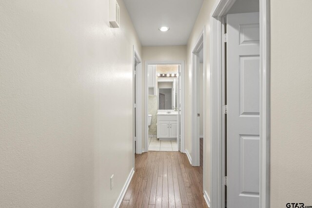 corridor with sink and light wood-type flooring