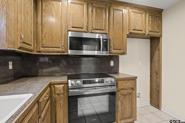 kitchen with stainless steel appliances, sink, light tile patterned floors, and backsplash