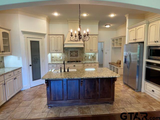 11200 Fox Trl, Flint, TX 75762 - kitchen featuring appliances with stainless steel finishes, crown molding, tasteful backsplash, a chandelier, and light stone countertops