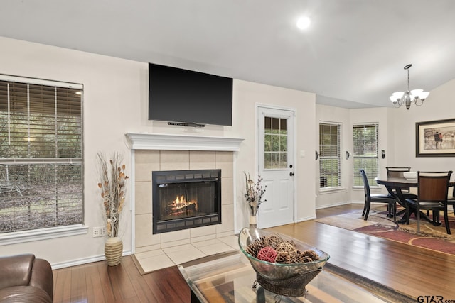 living room featuring a tile fireplace, hardwood / wood-style flooring, and an inviting chandelier