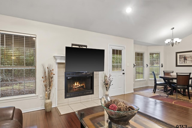 living room featuring a tile fireplace, an inviting chandelier, vaulted ceiling, and hardwood / wood-style flooring