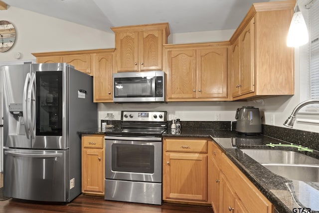 kitchen with sink, dark hardwood / wood-style flooring, dark stone counters, vaulted ceiling, and appliances with stainless steel finishes