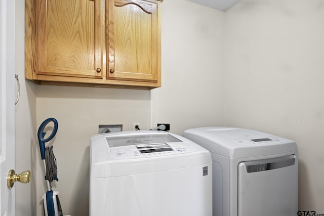 clothes washing area featuring cabinets and washing machine and clothes dryer