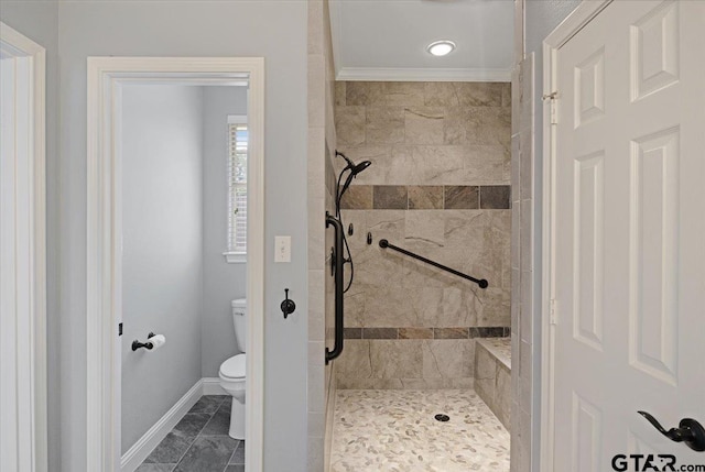 bathroom featuring ornamental molding, toilet, and a tile shower