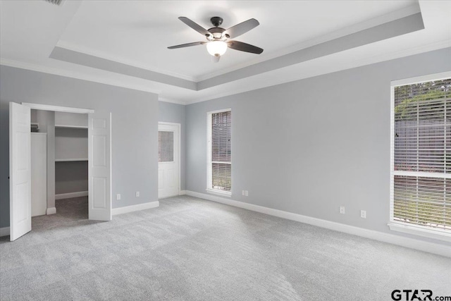 unfurnished bedroom with light carpet, ceiling fan, and a raised ceiling