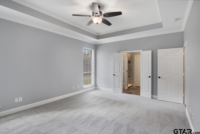 unfurnished bedroom with a tray ceiling, carpet, ceiling fan, and crown molding