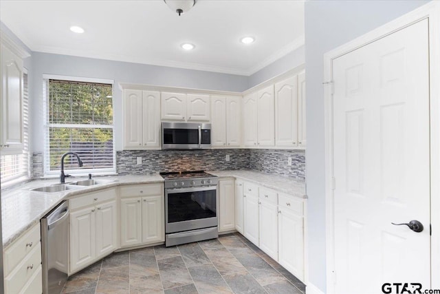 kitchen featuring tasteful backsplash, light stone countertops, appliances with stainless steel finishes, and sink