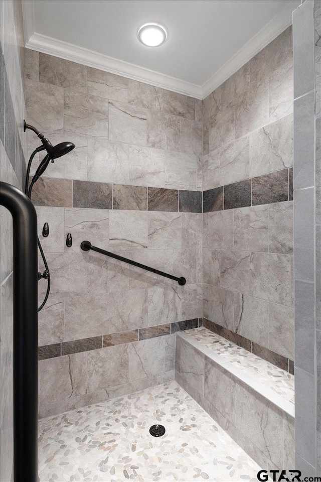 bathroom with a tile shower and ornamental molding