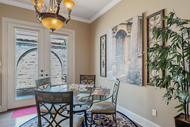 dining space with hardwood / wood-style floors, french doors, crown molding, and a notable chandelier