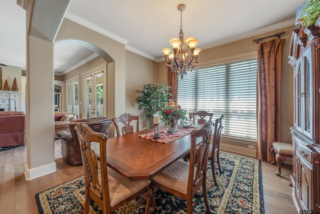 dining room with a notable chandelier, light wood-type flooring, and ornamental molding