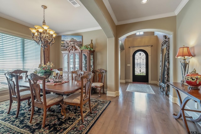 dining area with ornamental molding, hardwood / wood-style flooring, and a notable chandelier