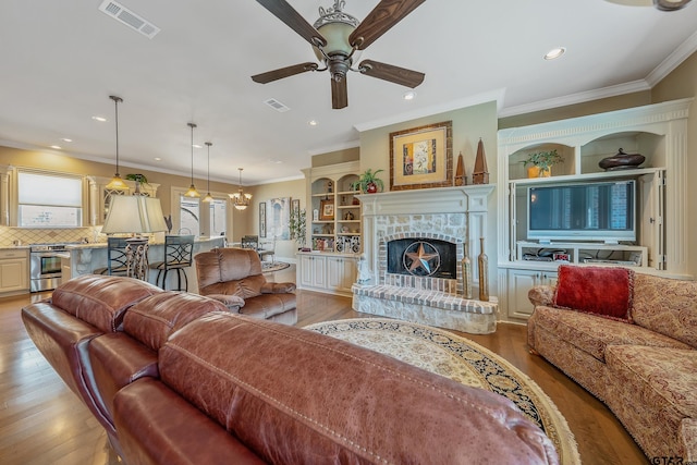 living room featuring crown molding, light hardwood / wood-style flooring, ceiling fan, and a brick fireplace