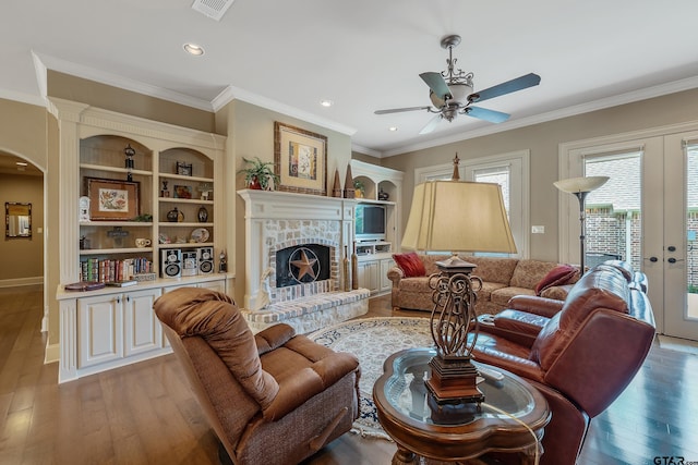 living room with crown molding, hardwood / wood-style floors, french doors, and a brick fireplace