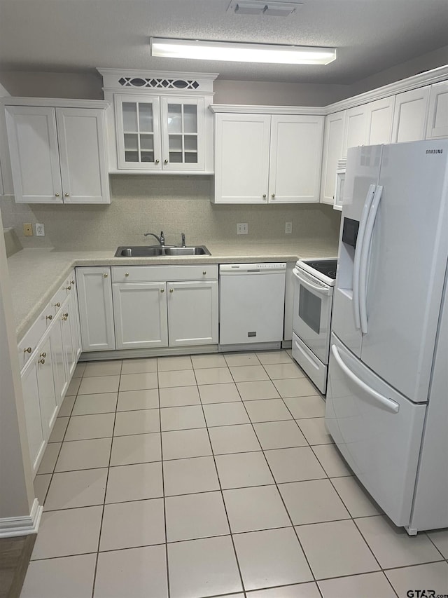 kitchen with white cabinetry, sink, light tile patterned flooring, and white appliances