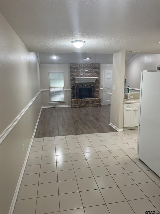 unfurnished living room featuring a fireplace, a textured ceiling, and light tile patterned floors