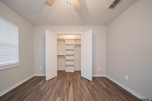 unfurnished bedroom with ceiling fan, dark hardwood / wood-style floors, a closet, and a spacious closet