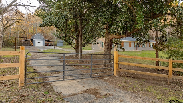 view of gate with a lawn and an outbuilding