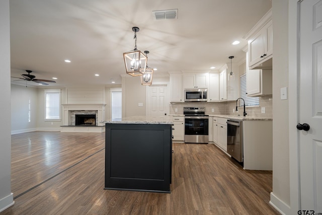 kitchen featuring backsplash, a center island, white cabinetry, stainless steel appliances, and hanging light fixtures