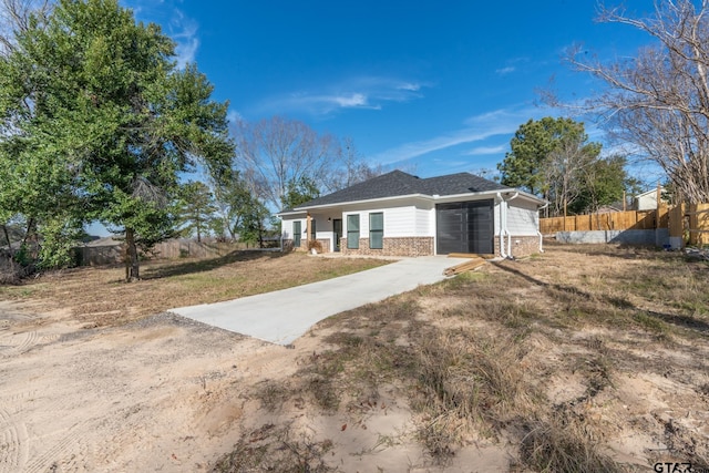 single story home featuring concrete driveway, brick siding, fence, and a front lawn