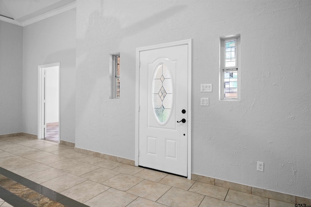 entryway with crown molding and light tile patterned floors