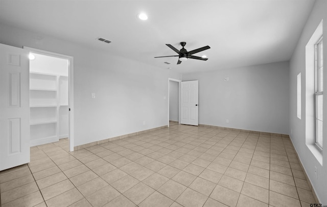 empty room featuring ceiling fan, built in shelves, and light tile patterned floors