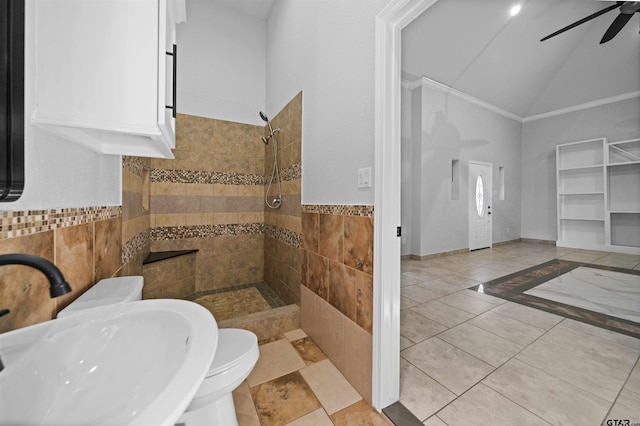 bathroom with sink, tile walls, vaulted ceiling, ceiling fan, and a tile shower