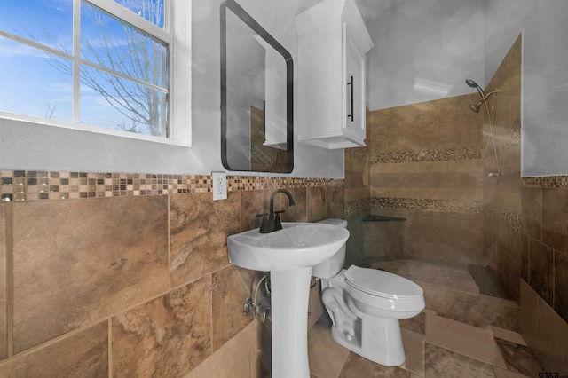 bathroom with tile walls, toilet, and a tile shower