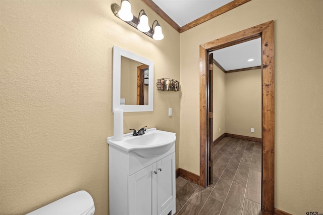 bathroom featuring ornamental molding, toilet, and vanity