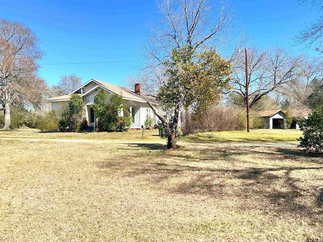 view of side of home featuring a lawn and a chimney