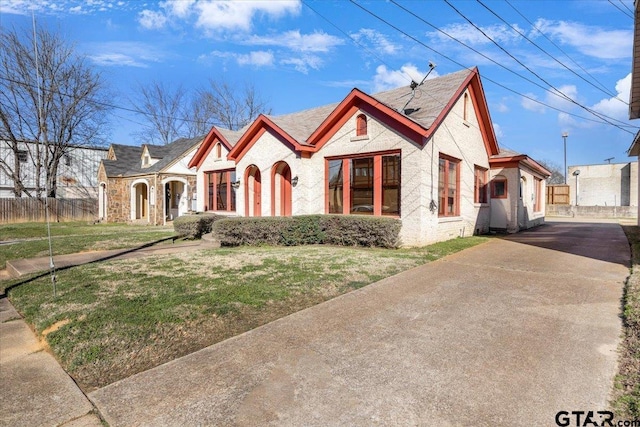 view of front of property with driveway, fence, and a front lawn